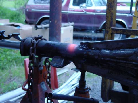 1979 Ford Bronco - Metal part being heated and worked on, with a vintage truck visible in the background.