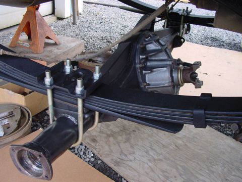 1979 Ford Bronco - The rear axle and leaf springs of a vehicle are shown, supported by an orange jack stand.