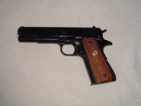 1995 Mercury Grand Marquis - A black semi-automatic pistol with textured brown grips is shown against a light-colored background.