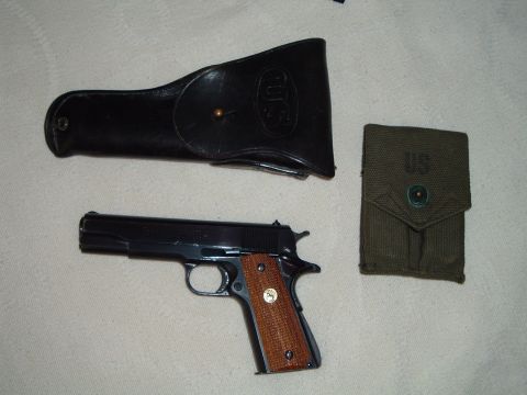 1995 Mercury Grand Marquis - A Colt M1911 pistol is displayed with its holster and a magazine pouch, all marked with US insignia.