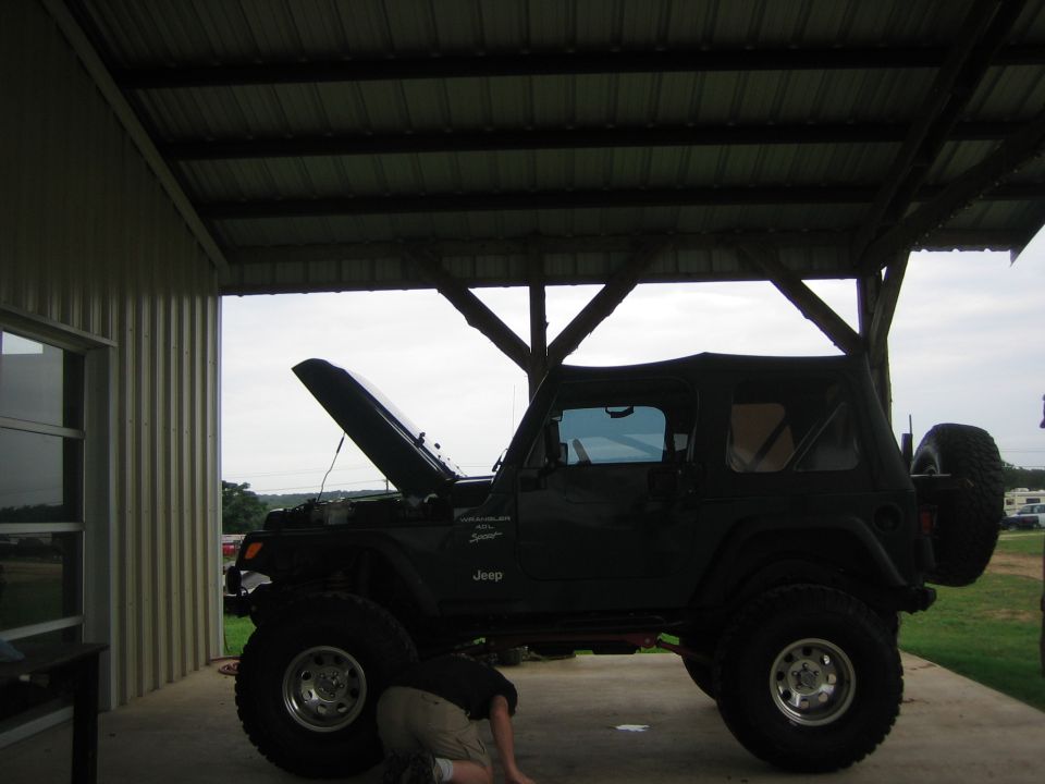 Dark green 2001 Jeep Wrangler with hood open, person working underneath