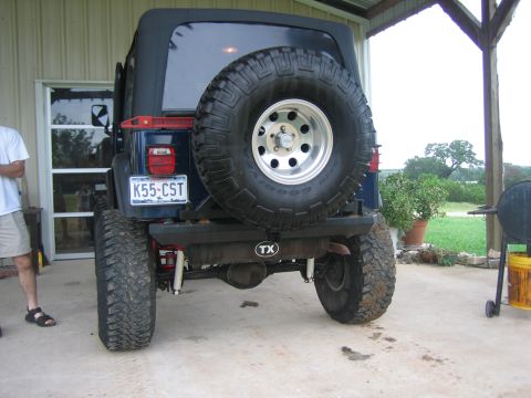 2001 Jeep Wrangler - The rear of a blue Jeep Wrangler is visible, equipped with a spare tire and a Texas license plate.