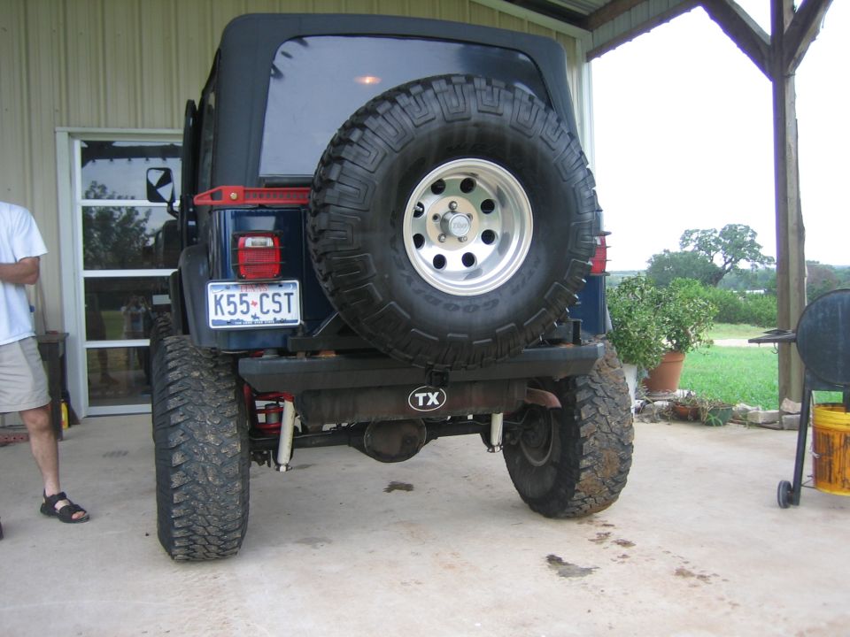 Blue Jeep Wrangler rear view with spare tire, license plate K55-CST, and TX hitch cover