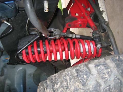 2001 Jeep Wrangler - Close-up view of a vehicle's front suspension system, highlighting a red coilover shock absorber and part of the tire.