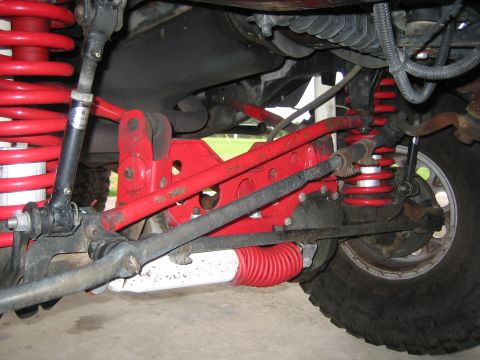 2001 Jeep Wrangler - Underneath view of red suspension parts and a tire on a Jeep Wrangler.