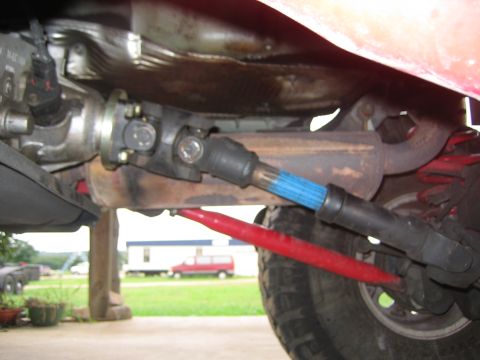 2001 Jeep Wrangler - Underside view of a vehicle's driveshaft and suspension system, red control arms and a driveshaft with blue splines.