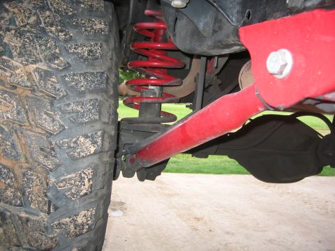 2001 Jeep Wrangler - The suspension system of an off-road vehicle is shown, focusing on the tire and red-painted components.