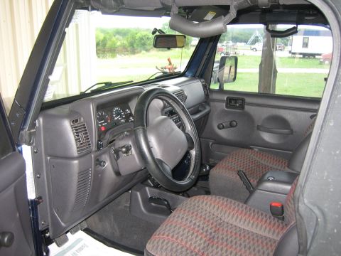 2001 Jeep Wrangler - The interior of a blue 2001 Jeep Wrangler is visible, the dashboard, steering wheel, and patterned seats.