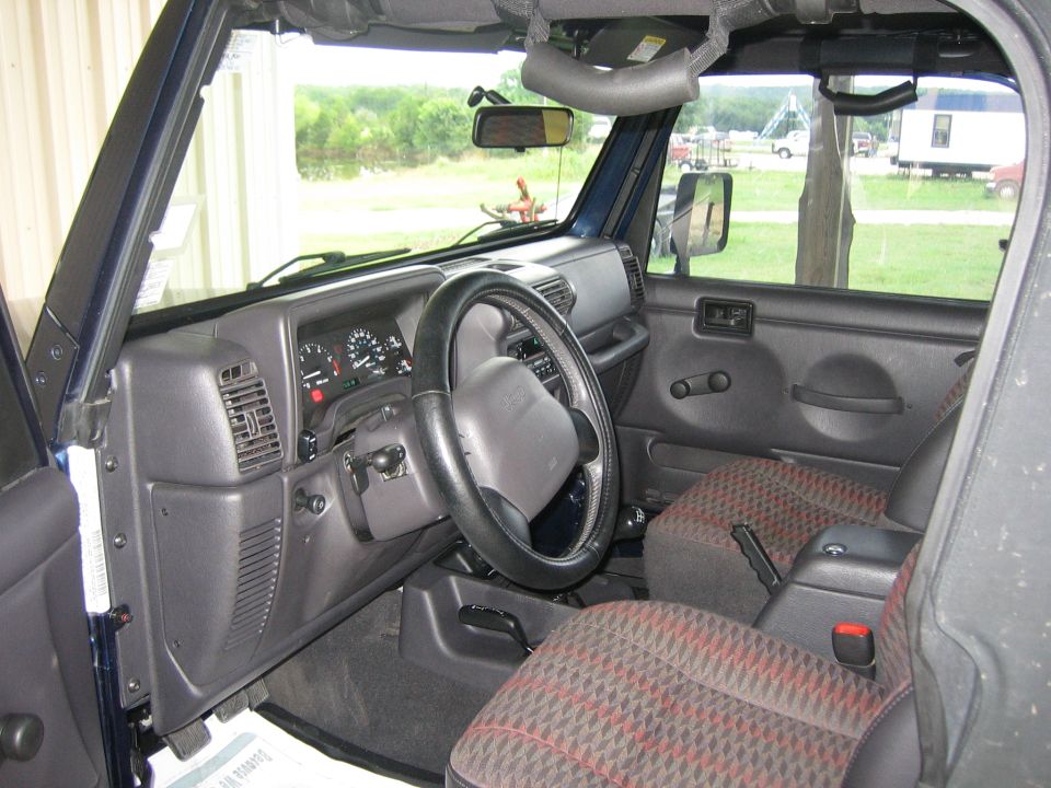 Interior of a blue 2001 Jeep Wrangler showing dashboard, steering wheel, and seats