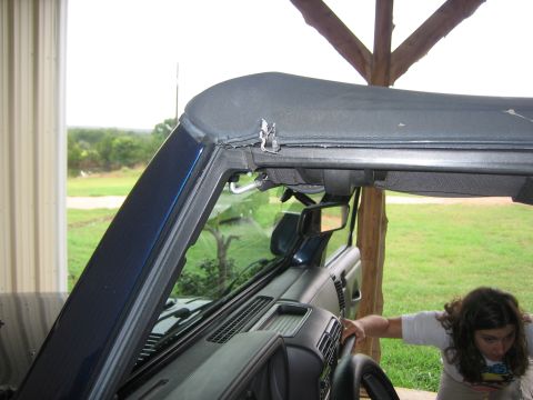 2001 Jeep Wrangler - A person is seen interacting with the interior of a Jeep Wrangler, focusing on the soft top mechanism.