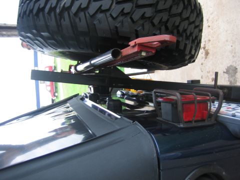 2001 Jeep Wrangler - A dark blue Jeep Wrangler's rear is partially visible, with a spare tire and jack mechanism mounted above it.