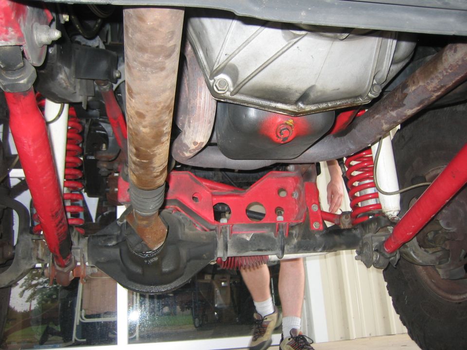 Underbody view of a vehicle with red suspension and driveshaft
