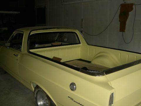 1967 Ford Ranchero - The rear bed of a yellow 1967 Ford Ranchero pickup truck is shown, with a sticker on the rear window reading "PANHEADS FOREVER".