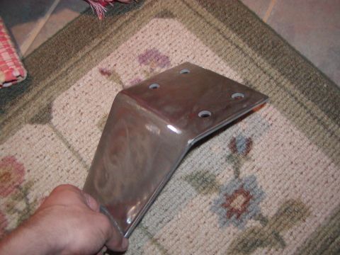 1991 Ford Bronco - A shiny metal bracket with four bolt holes is held by a hand over a patterned rug.