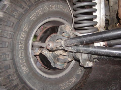 1991 Ford Bronco - Detailed view of the steering and suspension system of an off-road vehicle, showing the linkage and coil spring.