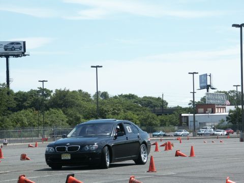 2001 Mercury Grand Marquis - A black BMW 7 Series navigates an autocross course marked by orange cones under a clear sky.