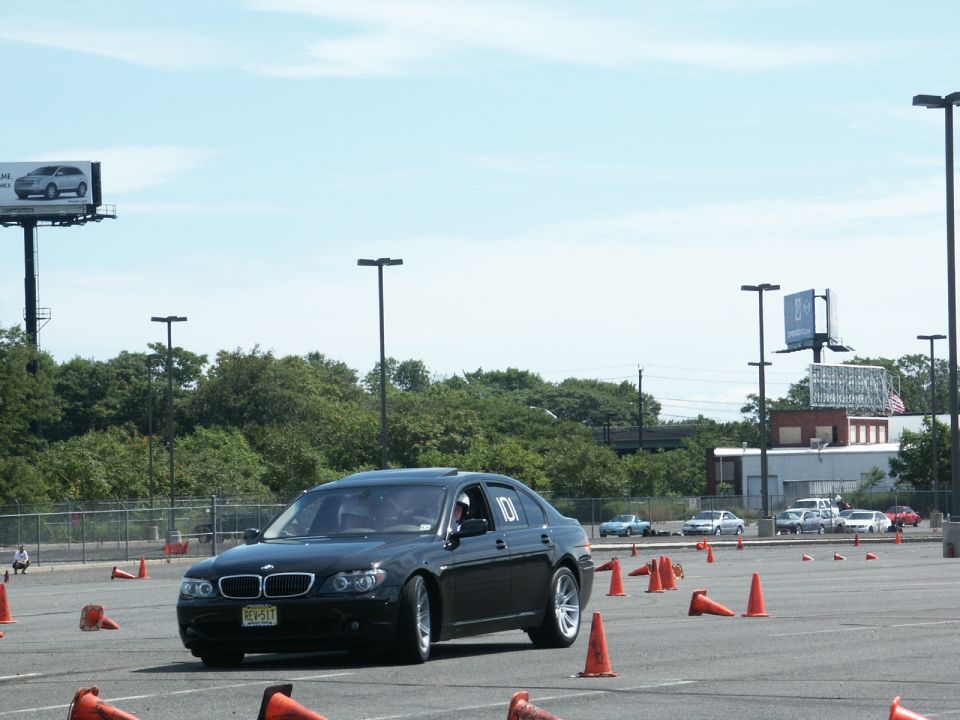 Black BMW 7 Series driving on a course with orange cones. Number 101 on the door