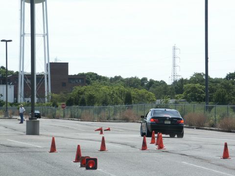 2001 Mercury Grand Marquis - A black sedan navigates an autocross course marked by orange cones, with a water tower visible in the distance.