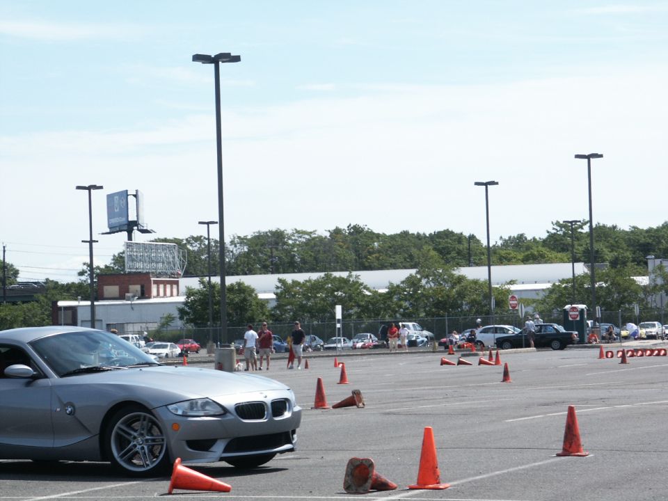 Silver BMW Z4 parked in a lot with orange cones and other cars in the background