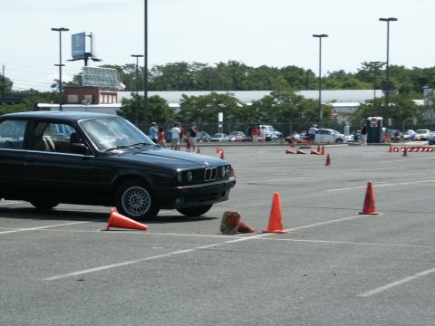 2001 Mercury Grand Marquis - A black BMW E30 sedan is seen on a paved course marked with orange cones, likely during an autocross event.
