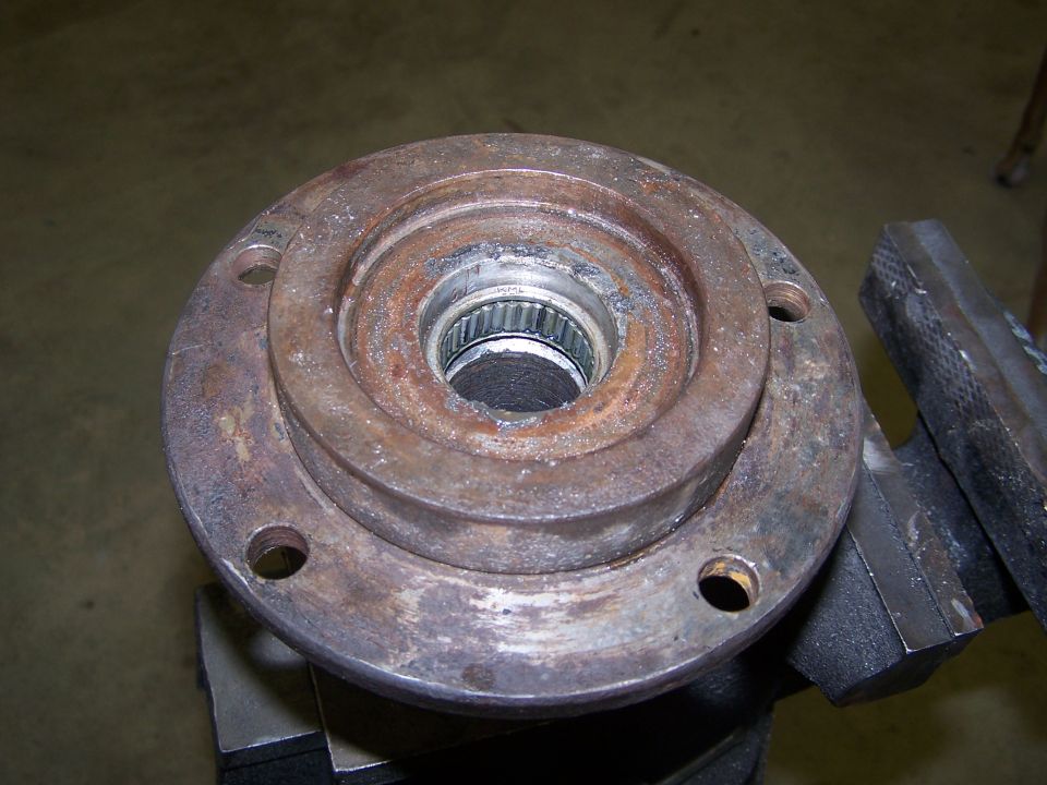 rusted wheel hub assembly with splines visible in the center, held in a vise