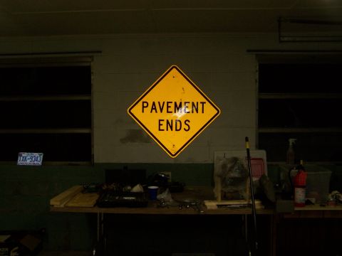 1979 Ford Bronco - A 'Pavement Ends' sign is mounted on a wall in a workshop setting, with a table of tools below.