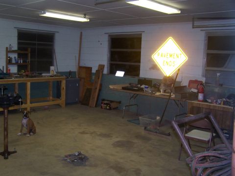 1979 Ford Bronco - A boxer dog is in a garage with a workbench and a glowing "PAVEMENT ENDS" sign.