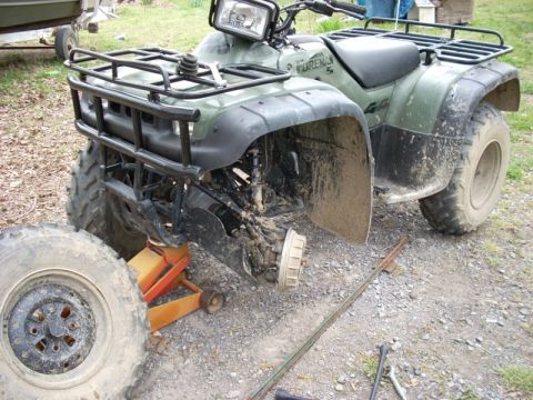 1999 Honda FOURTRAX FOREMAN S - This ATV has a damaged front wheel assembly and is missing its front tire, which lies beside it.