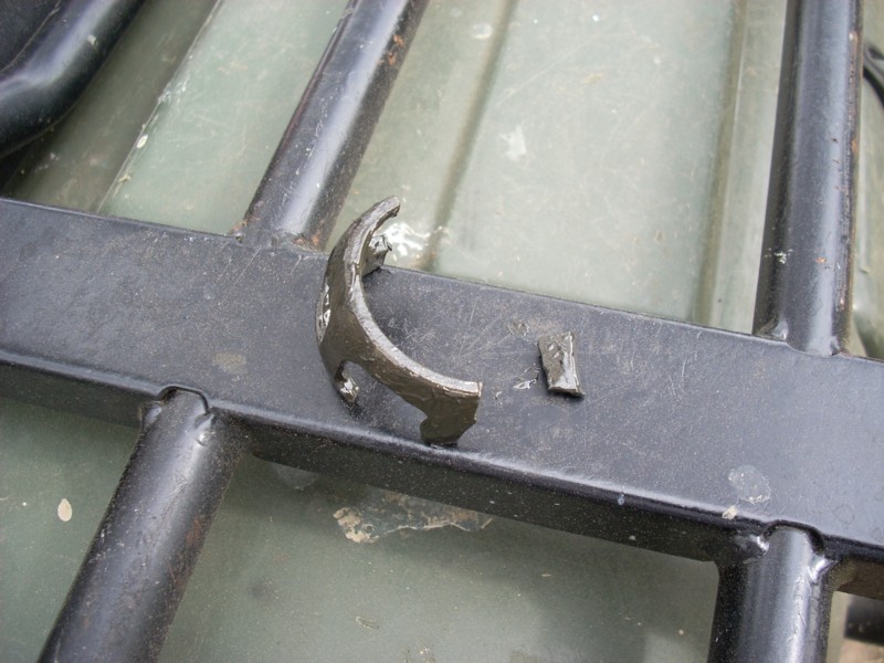 Broken curved metal brake shoe fragment resting on a black tubular rack bar