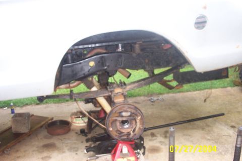 1979 Ford F-150 - The rear suspension and axle of a white pickup truck are visible, undergoing maintenance or repair.