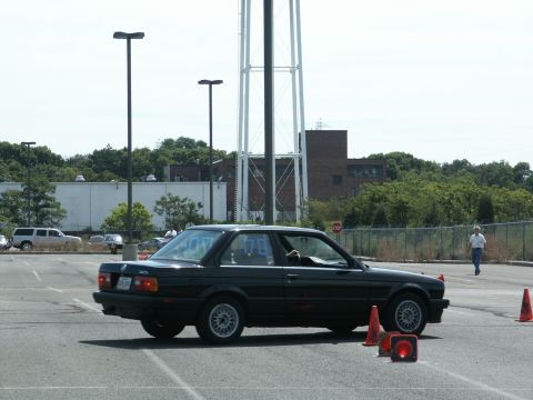 2001 Mercury Grand Marquis - A black BMW 3 Series is seen on a race course with traffic cones, under a bright sky.