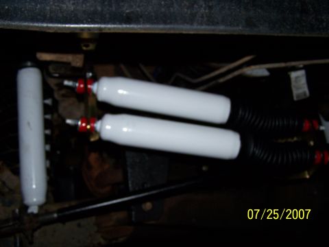 1979 Ford F-150 - Close-up view of two white shock absorbers mounted on a vehicle's underside.