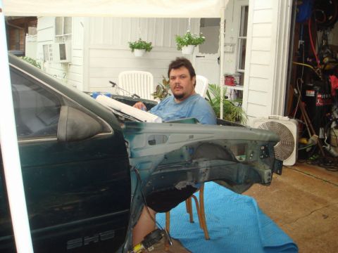 1993 Ford Taurus - A man sits in the interior of a disassembled car, with the fender removed.