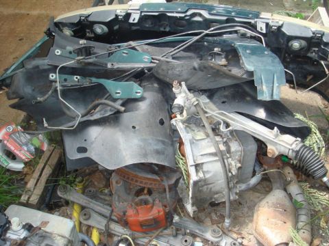 1993 Ford Taurus - A jumbled collection of damaged vehicle parts, primarily from the front end, lies in disarray.