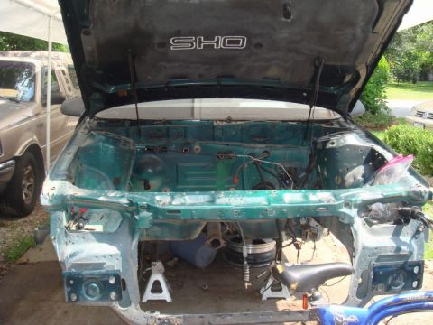 1993 Ford Taurus - The engine bay of a green car, with the hood open and parts removed, is shown with an SHO emblem on the liner.