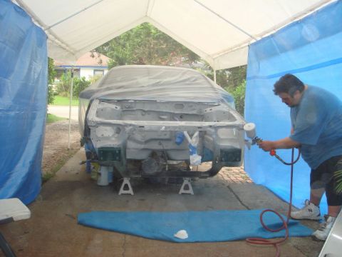 1993 Ford Taurus - Car body undergoing spray painting in a makeshift booth.