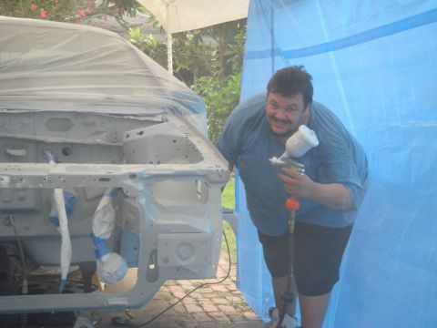 1993 Ford Taurus - Man with paint sprayer next to car body being prepped for paint.