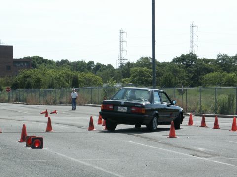 2001 Mercury Grand Marquis - A black BMW E30 navigates an autocross course marked by orange cones on a paved lot.