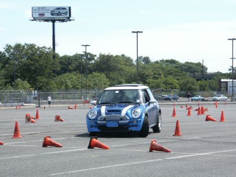 2001 Mercury Grand Marquis - A blue Mini Cooper navigates a cone course on a sunny day, with other cars visible in the background.