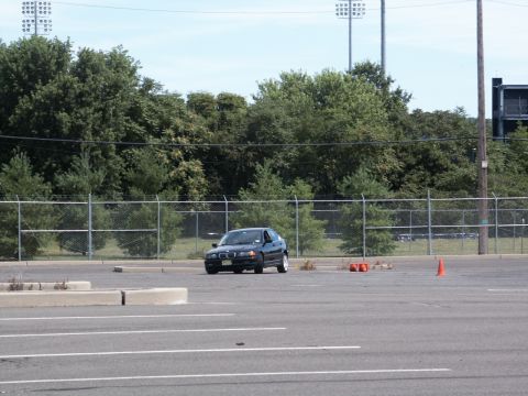 2001 Mercury Grand Marquis - A dark sedan navigates an autocross course marked by orange cones on a sunny day.
