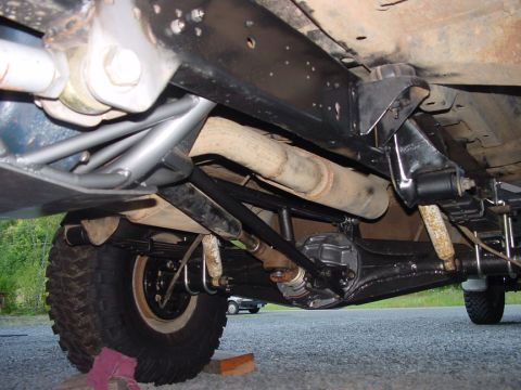 1979 Ford Bronco - Undercarriage view shows the rear axle, driveshaft, and a prominent traction bar modification.