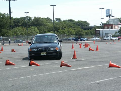 2001 Mercury Grand Marquis - A BMW navigates a cone course in a parking lot, with other cars visible in the background.