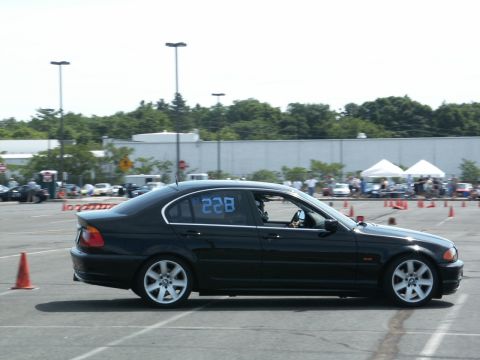 2001 Mercury Grand Marquis - A black BMW 3 Series sedan navigates an autocross course, indicated by orange cones and racing numbers on the window.