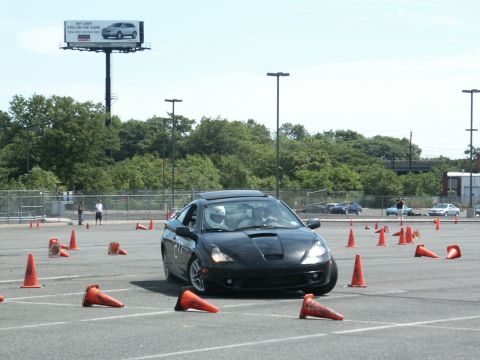 2001 Mercury Grand Marquis - A black Toyota Celica GT-S navigates an autocross course marked by orange cones under a bright sky.