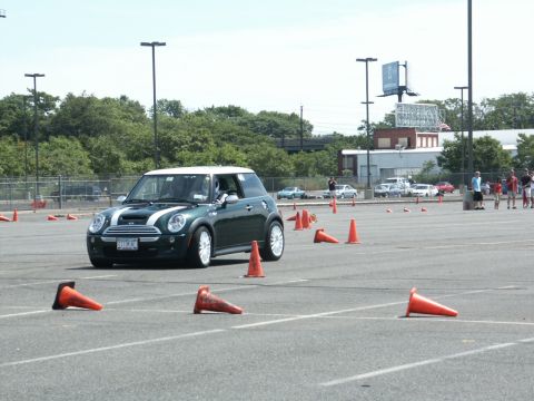 2001 Mercury Grand Marquis - A green Mini Cooper participates in an autocross event on a sunny day, with other vehicles and spectators in the background.