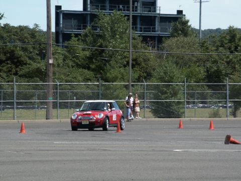 2001 Mercury Grand Marquis - A red Mini Cooper with a white roof drives through an autocross course, marked by orange cones.
