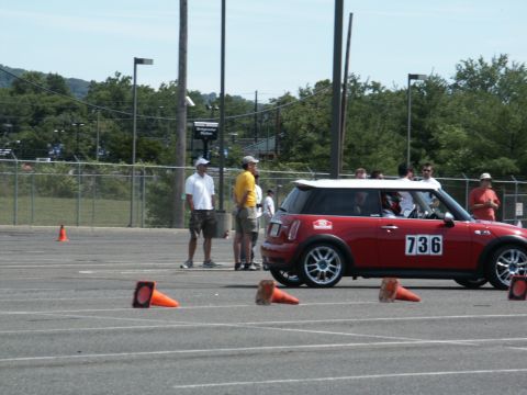 2001 Mercury Grand Marquis - A red Mini Cooper with a white roof is parked on an asphalt lot, marked with orange cones for an event.