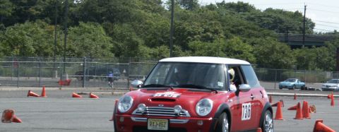 2001 Mercury Grand Marquis - Red Mini Cooper navigates a course marked by orange cones, with other vehicles in the distance.