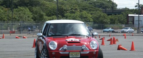 2001 Mercury Grand Marquis - A red Mini Cooper navigates an autocross course marked by orange cones, with other vehicles visible in the distance.
