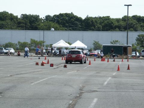 2001 Mercury Grand Marquis - A red Mini Cooper navigates an autocross course with several other vehicles and tents visible in the background.